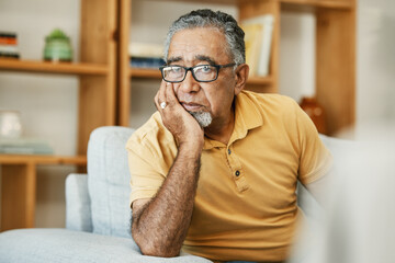 Face, mental health and thinking with a sad old man on a sofa in the living room of his retirement...