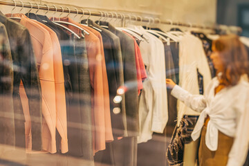 Young woman looking new clothes in fashion store in boutique, shopping concept. Blurred view...