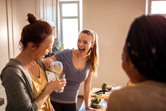 Young woman pouring a healthy shake for her friend in the kitchen