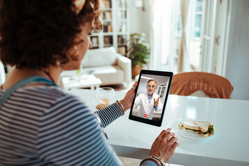 Young woman having a video chat with her doctor on the tablet at home