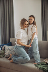 Cheerful mom playing laughing with little daughter on sofa, playful young mother having fun with pretty cute baby.