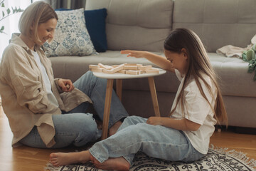 A happy mother and her little daughter have fun playing a board game. Mother and daughter play...
