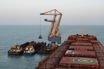 floating crane discharging coal from a anchored cape size bulk carrier