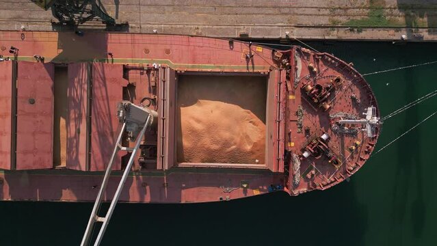 cargo ship or bulk carrier loaded to the brim with grain is preparing for departure, working sailors on deck are completing work, aerial view