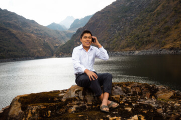 Fototapeta premium Una foto de una chico campesino alumno caucásico usando un smartphone durante la publicidad en un parque, Hombre nativo quechua con celular, estilo de vida,Comunicación