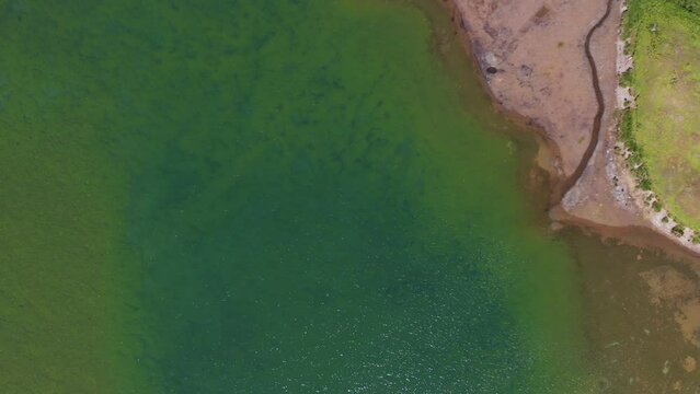 Tignes - Flying with a drone over a beautiful green lake lost in mountains in summer