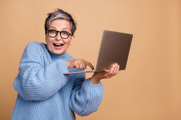 Portrait of astonished positive person use wireless netbook finger press button empty space isolated on beige color background