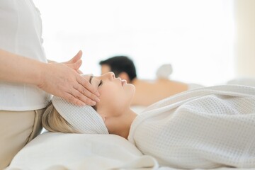 Young couple receiving head massage at beauty spa. Relaxed Husband And Wife At Exotic Spa Resort.