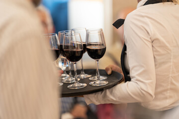 Waiters serve glasses of red wine at a social party