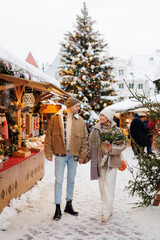 Happy couple with bouquet walking at the christmas market