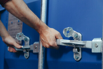Close up view on man hands is opening the lock of large shipping container doors