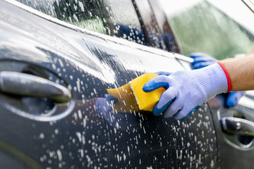 Man washing car with yellow sponge outdoors - obrazy, fototapety, plakaty