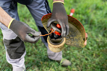 Man pulls the line out of the weed trimmer coil - maintenance of garden tools. - obrazy, fototapety, plakaty