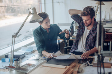 Two young Caucasian male architects working on a project together in a modern business office