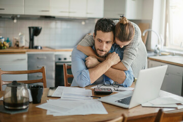 Young couple embracing each other during a financial crisis at home