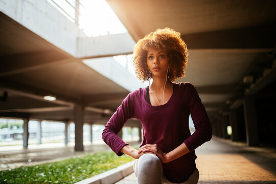 Young fit woman stretching before jogging under a bridge in the city