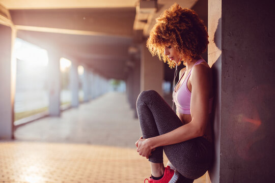 Young fit woman stretching before jogging under a bridge in the city