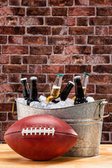 A close-up of the white laces of an American football sitting in front of a galvanized tub with...