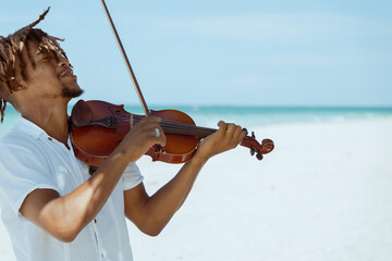 stylish passionate musician playing violin on the beach