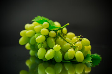 A bunch of ripe green grapes with leaves.