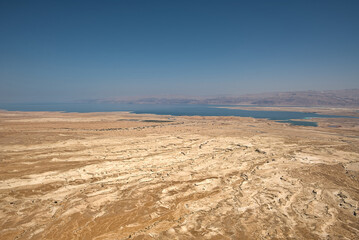 Fototapeta na wymiar From Masada, Israel, gaze eastward to a breathtaking vista. The vast desert sprawls beneath, and the shimmering Dead Sea, nature's mirror, glimmers in the distance, creating a mesmerizing panorama.