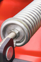 Steel silver spring as part of red agricultural machine. Technology