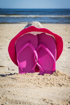 Straw hat and slippers on sand at beach. Accessories for relax in summer