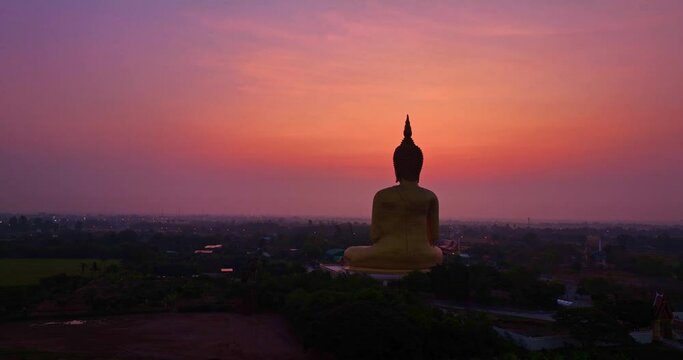 .aerial view colorful pink sky in sunrise at golden big buddha a popular landmark in Thailand..bright pink sky background. .golden big buddha in the rice field popular landmark of Thailand.