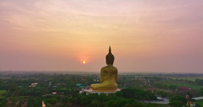 ..aerial view colorful sky in sunrise the yellow sun at golden big buddha a popular landmark in Thailand..video 4K Nature video High quality footage for worship and travel concept..green rice field.