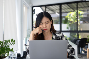 Young woman engages in online study at workspace.