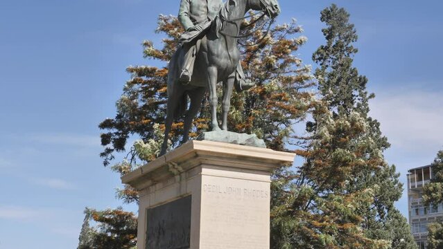 Kimberley, South Africa - September 2023: medium shot of Cecil Rhodes statue atop horse. Tilt down from bronze sculpture to granite plinth.