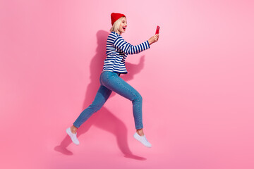 Full length photo of sweet shiny lady wear striped shirt jumping chatting instagram twitter...