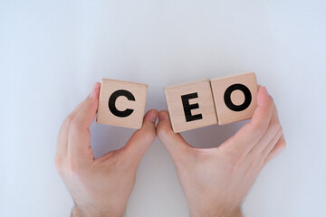 Man hands holding wooden cubes with CEO letters on them, boss or Chief Executive Officer idea, wooden block cubes with CEO word, wood blocks on white background, top view