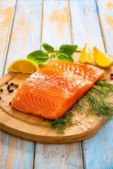 Fresh raw salmon steak with salt and fresh vegetables on wooden background
