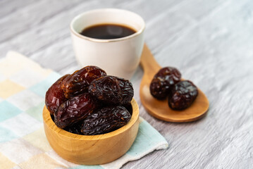 Dried dates fruit in wooden bowl with a cup of coffee.
