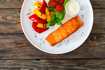 Seared salmon steak with grilled bell pepper and mayonnaise on wooden table
