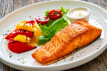 Seared salmon steak with grilled bell pepper and mayonnaise on wooden table
