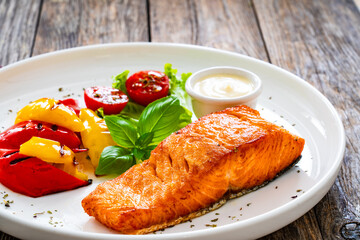 Seared salmon steak with grilled bell pepper and mayonnaise on wooden table
