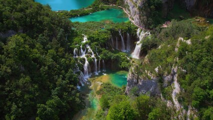 Mountain lake with streams of water and waterfalls. People hiking on narrow path in Plitvice National Park Croatia.