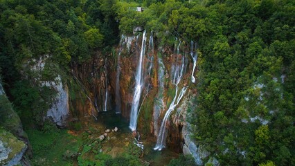 Scenic high waterfall cascading over lush green cliff in dense forest. Mountain stream with clear...