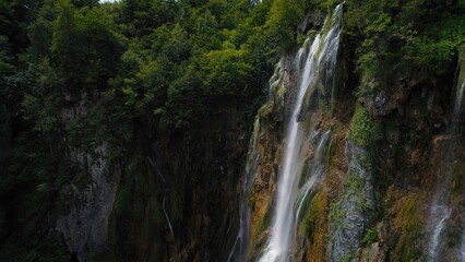 Amazing waterfall falling from a high cliff in lush green forest. Mountain cascade with clear water.