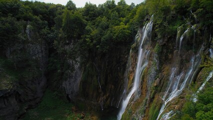Amazing waterfall falling from a high cliff in lush green forest. Mountain cascade with clear water.