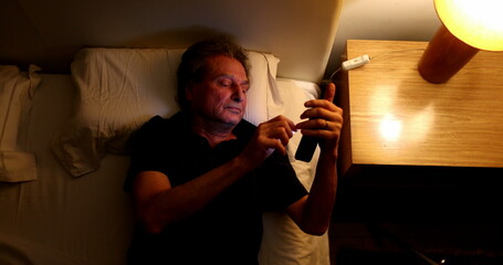 Man turning off phone and nightstand lamp light, person going to sleep