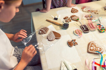 Children decorating gingerbread cookies with glaze on table at home - 656618021