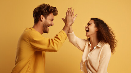 Side view of cheerful boyfriend and girlfriend giving high - five to each other and screaming over beige background. Excited young couple clapping hands and celebrating success - obrazy, fototapety, plakaty