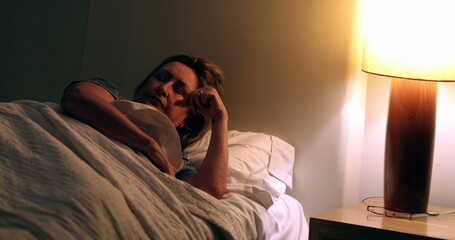 Person turning nightstand light on. Senior woman waking up in the middle of the night suffering...