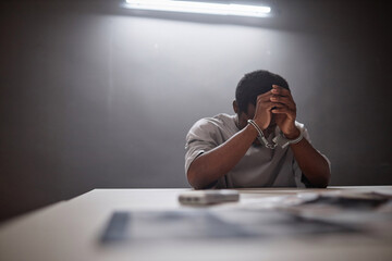 Minimal portrait of Black young man wearing handcuffs crying in remorse as criminal arrested, copy...