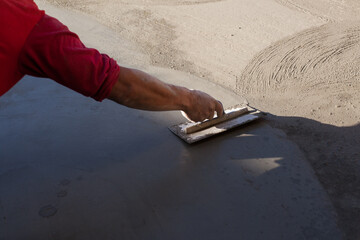 Close-up photo of a hand finishing a cement slab. Construction concept. - obrazy, fototapety, plakaty