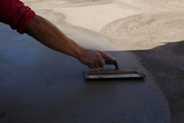 Close-up photo of a hand finishing a cement slab. Construction concept. - obrazy, fototapety, plakaty
