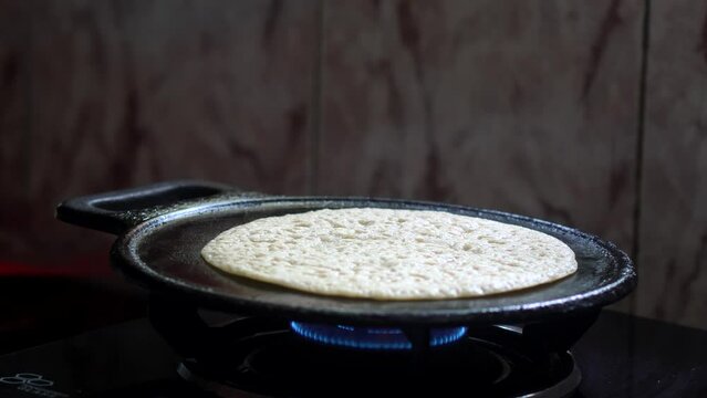 Flipping wheat dosa on cast iron tawa while cooking.  Cooking healthy and delicious South Indian  cuisine, wheat dosa.